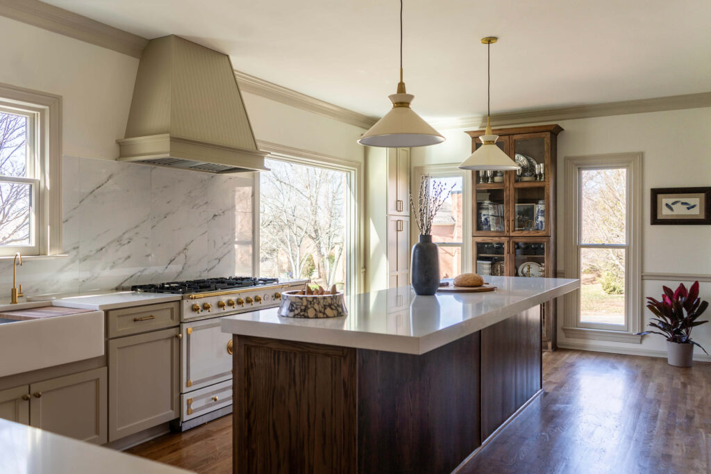 A wide view of a custom kitchen design by Holly Thompson Design, with a large island, La Cornue range and wood hood vent.