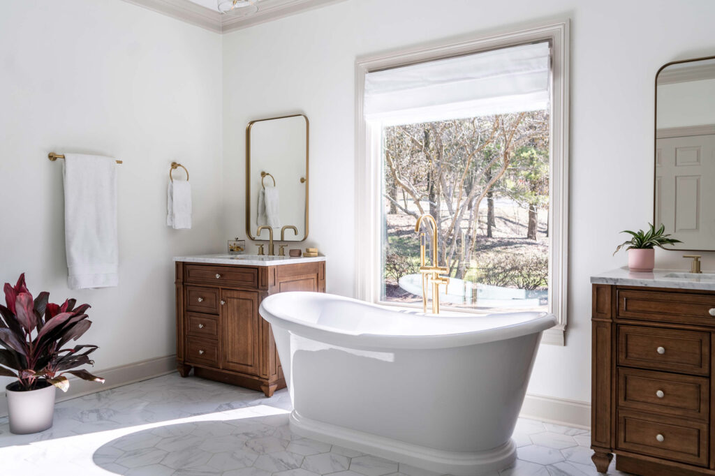 Bathroom with luxury home design through a freestanding bath tub, marble flooring and dark wood vanities.