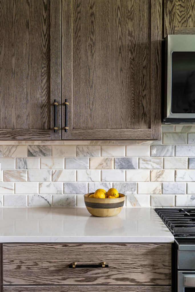 A close up of the guest cottage kitchen countertops with a marble subway tile backsplash and dark wood finish cabinets.