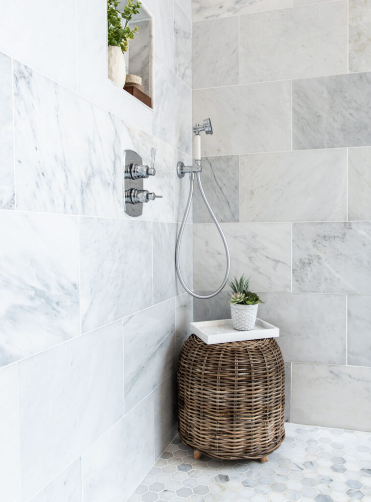 A marble bathroom shower with large blocks of marble for the shower surround and hexagonal tiles for the floors.