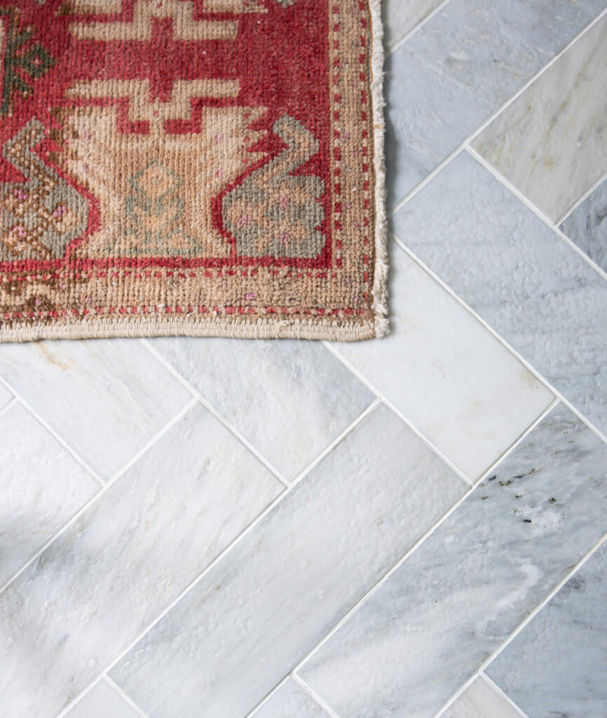 Marble subway tile in a herringbone pattern with white grout