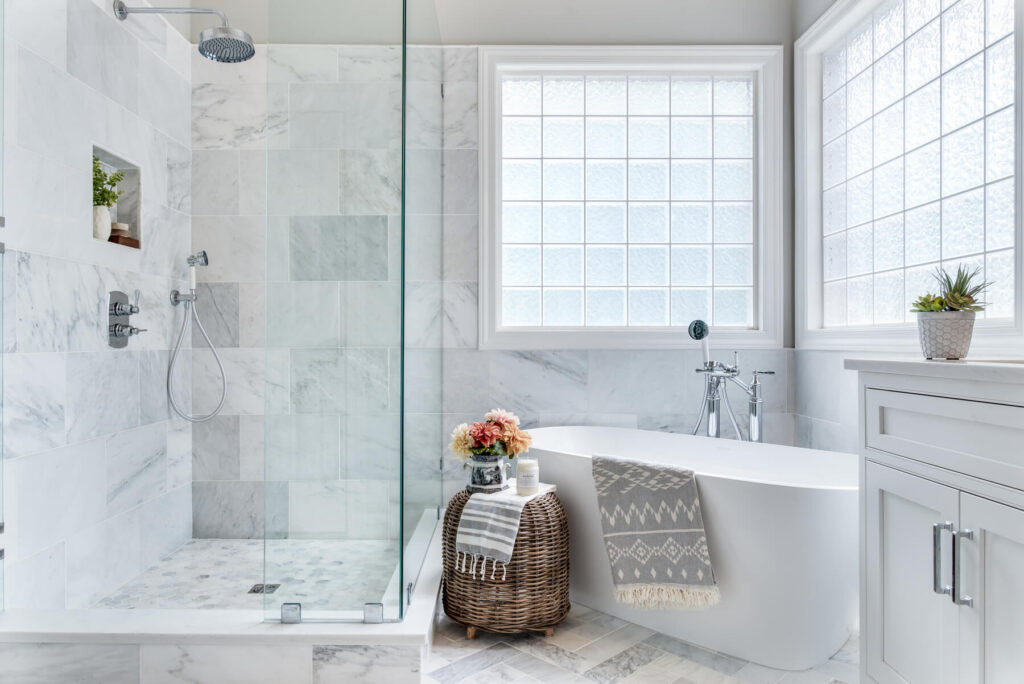 Overall view of this marble shower with two windows, white vanities and lots of marble in and around the glass shower