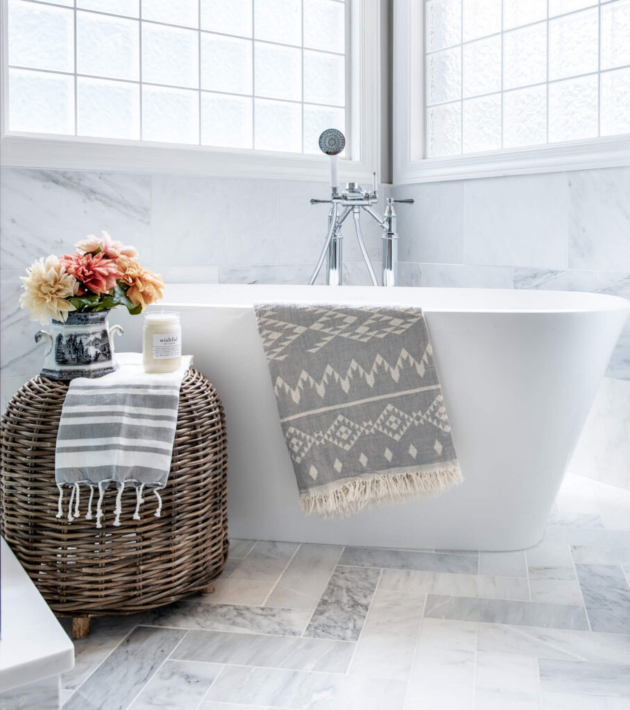 The volcanic limestone freestanding bathtub with herringbone patterned floor tiles