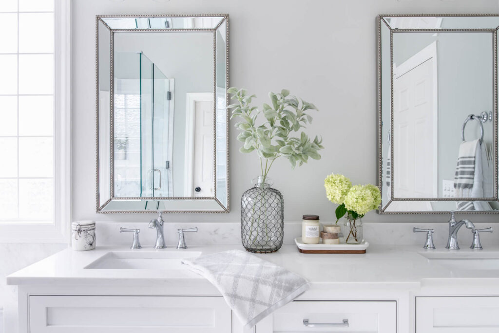 The top of the white custom bathroom vanities with two vertical mirrors and a bathroom tray on the counter